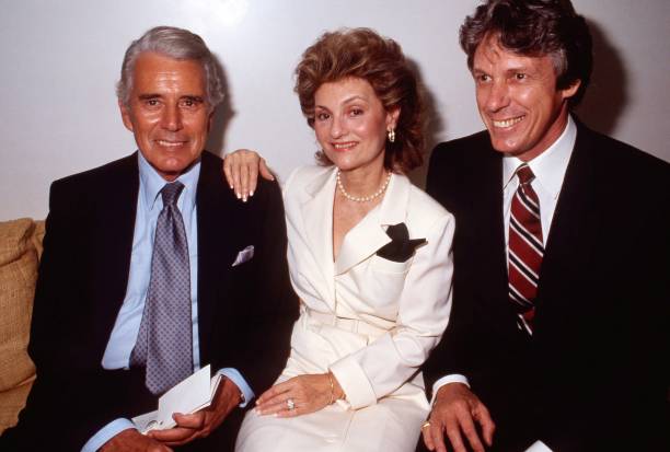 LOS ANGELES - SEPTEMBER 19: Actor John Forsythe and his wife Julie sit with designer Nolan Miller at a private showing of "The Dynasty Collection" on Sept 19, 1987 in Los Angeles, California. The showing is to showcase some of the costumes designed by Nolan Miller, that appear on the series. (Photo by Joan Adlen/Getty Images)