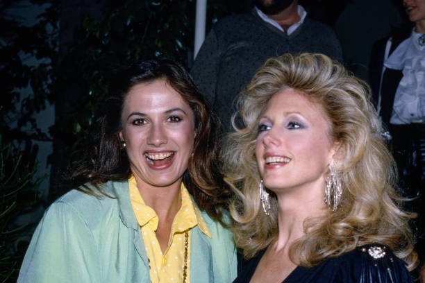 Mexican-American actress Ana Alicia, wearing a pale green jacket over a yellow outfit with white polka dots, and American actress Morgan Fairchild, who wears a black outfit with shoulder studs and fringed drop earrings, at Spago, a restaurant on the Sunset Strip in West Hollywood, California, 28th September 1985. (Photo by Vinnie Zuffante/Getty Images)